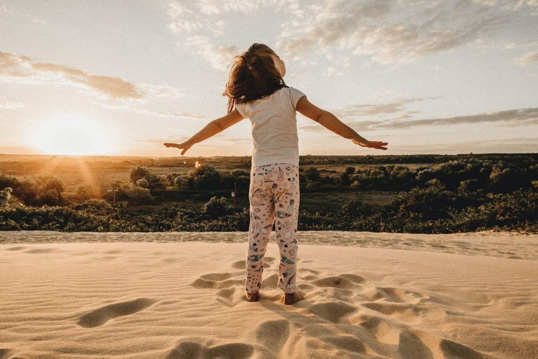 Little girl spreading arms on the beach