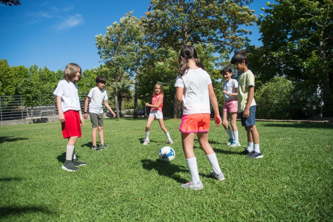 Group of Kids Playing Football at the Field