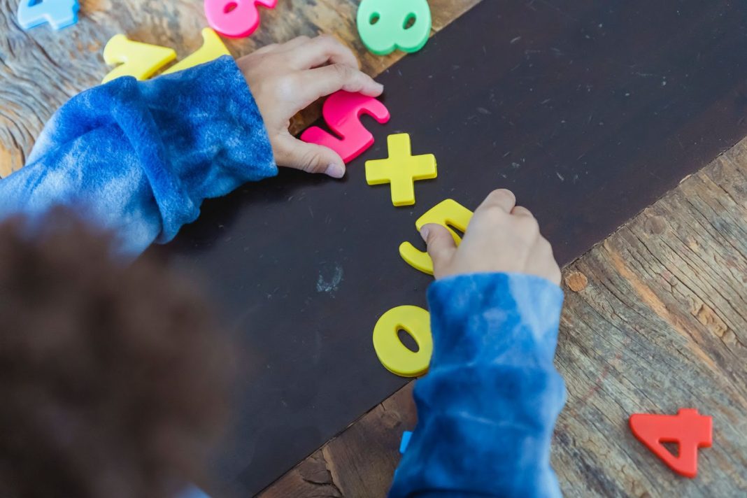 Boy solving mathematical example made of toy numbers