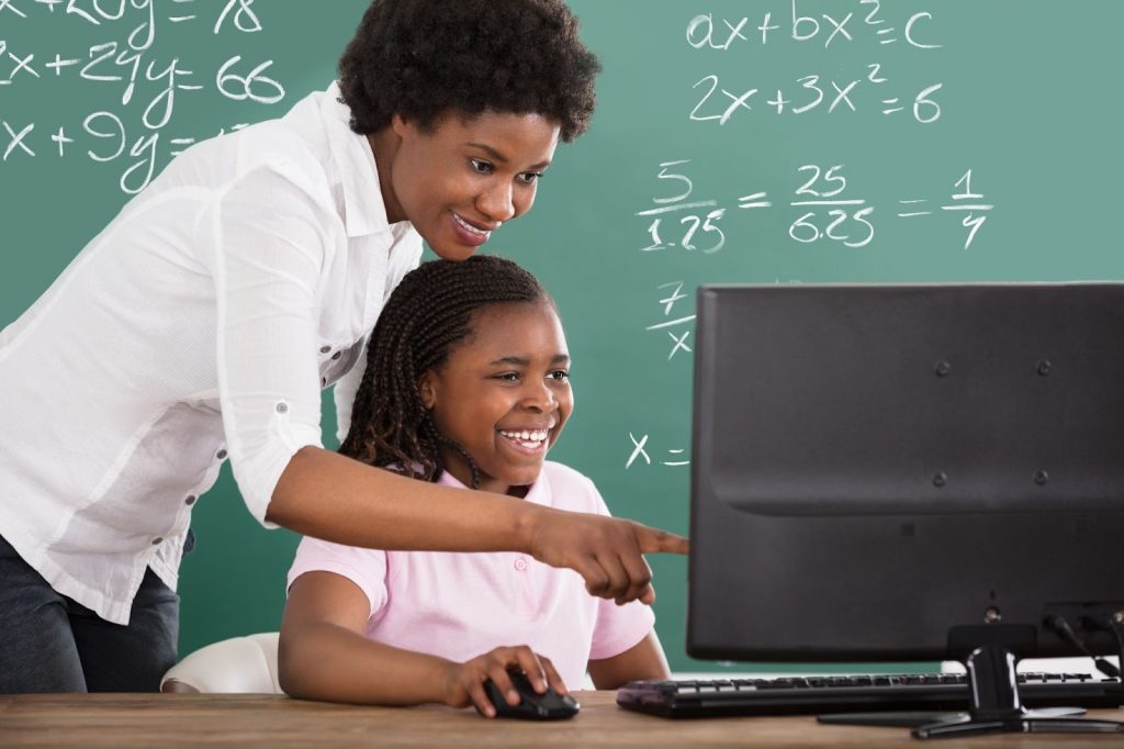 A teacher and kid using a computer in class