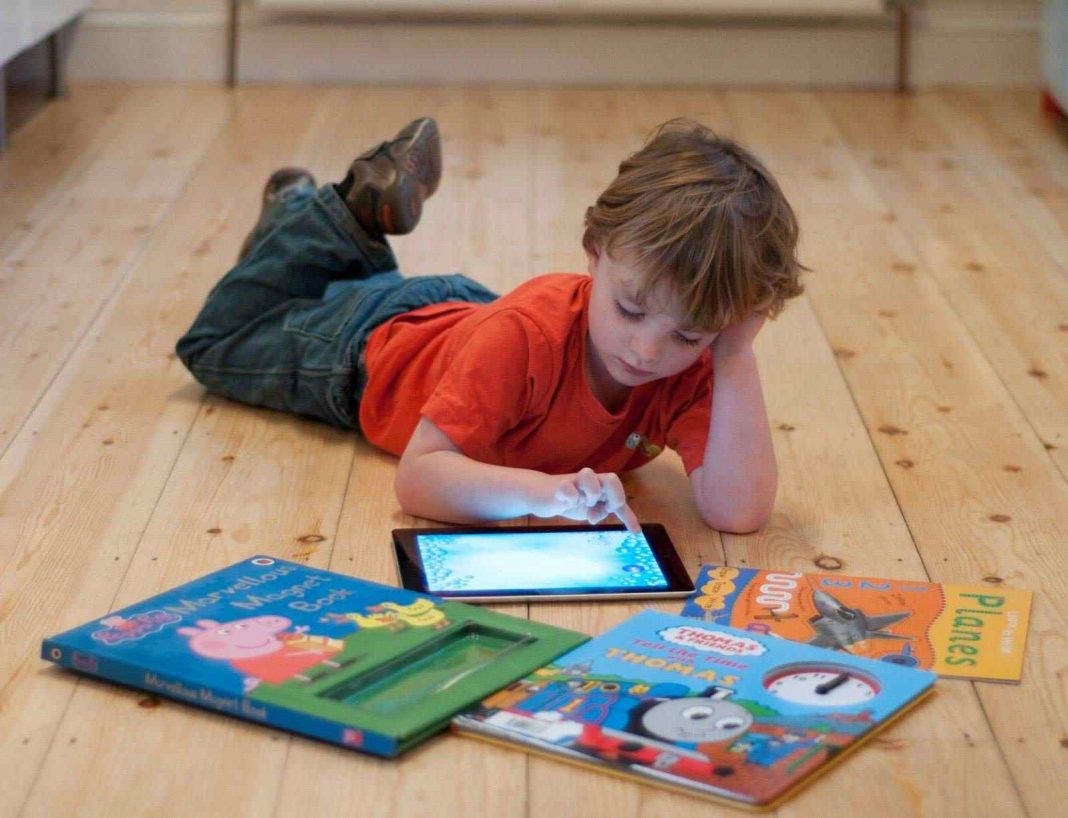 Kid using an iPad lying on the floor