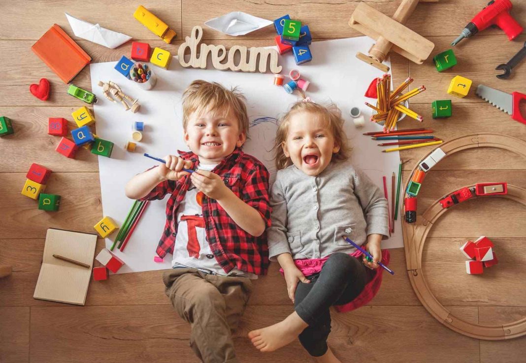 Two kids smiling and lying on the floor