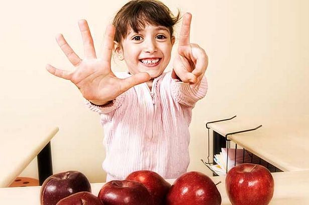A kid counting with apples