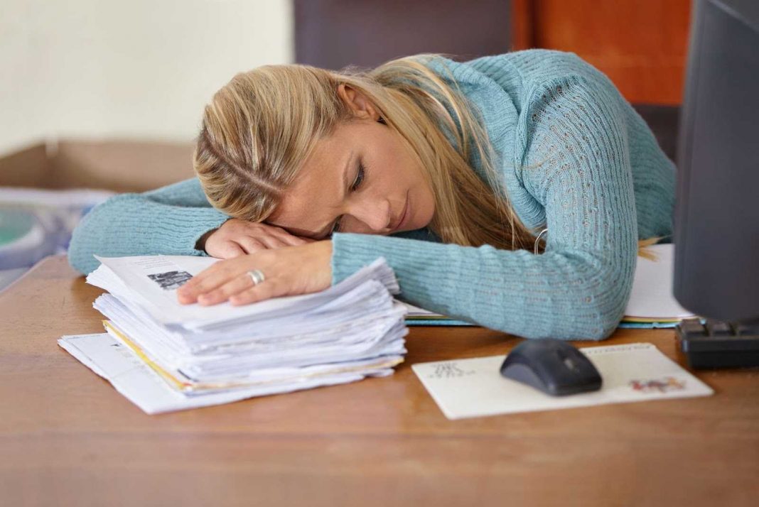 Teacher laying head on papers under stress