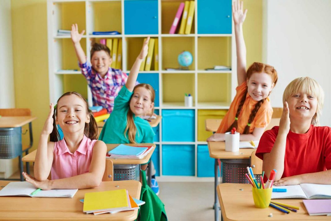 Children in a classroom raising their hands to answer questions