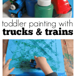 Image of toddler painting with trucks trains toys