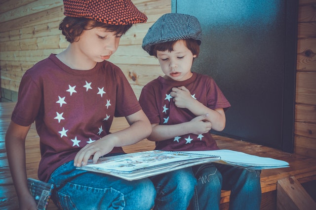 Image of two kids sitting together and reading a book