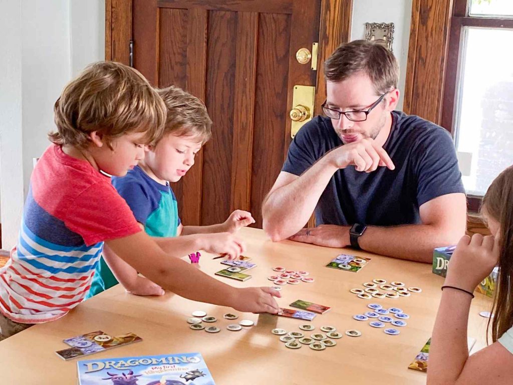 A dad is playing an educational board game with his four year old kids