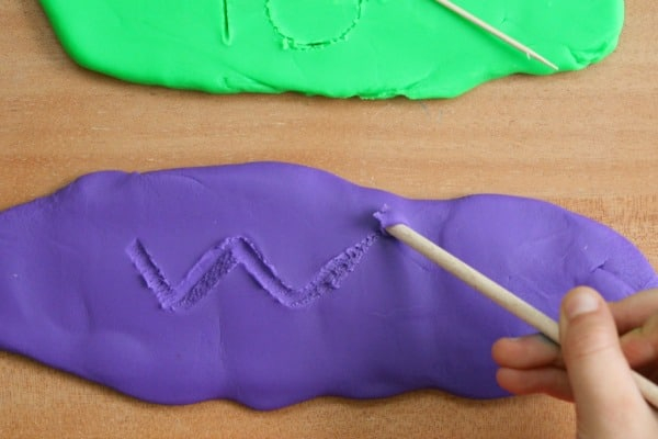 Child writing on play dough