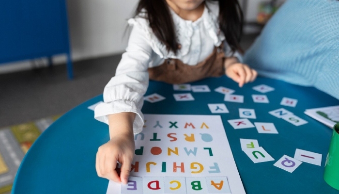 A picture of an alphabet activity where a girl is matching and arranging alphabet cards in the correct order