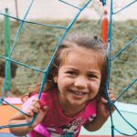 Young girl playing outside looking through net